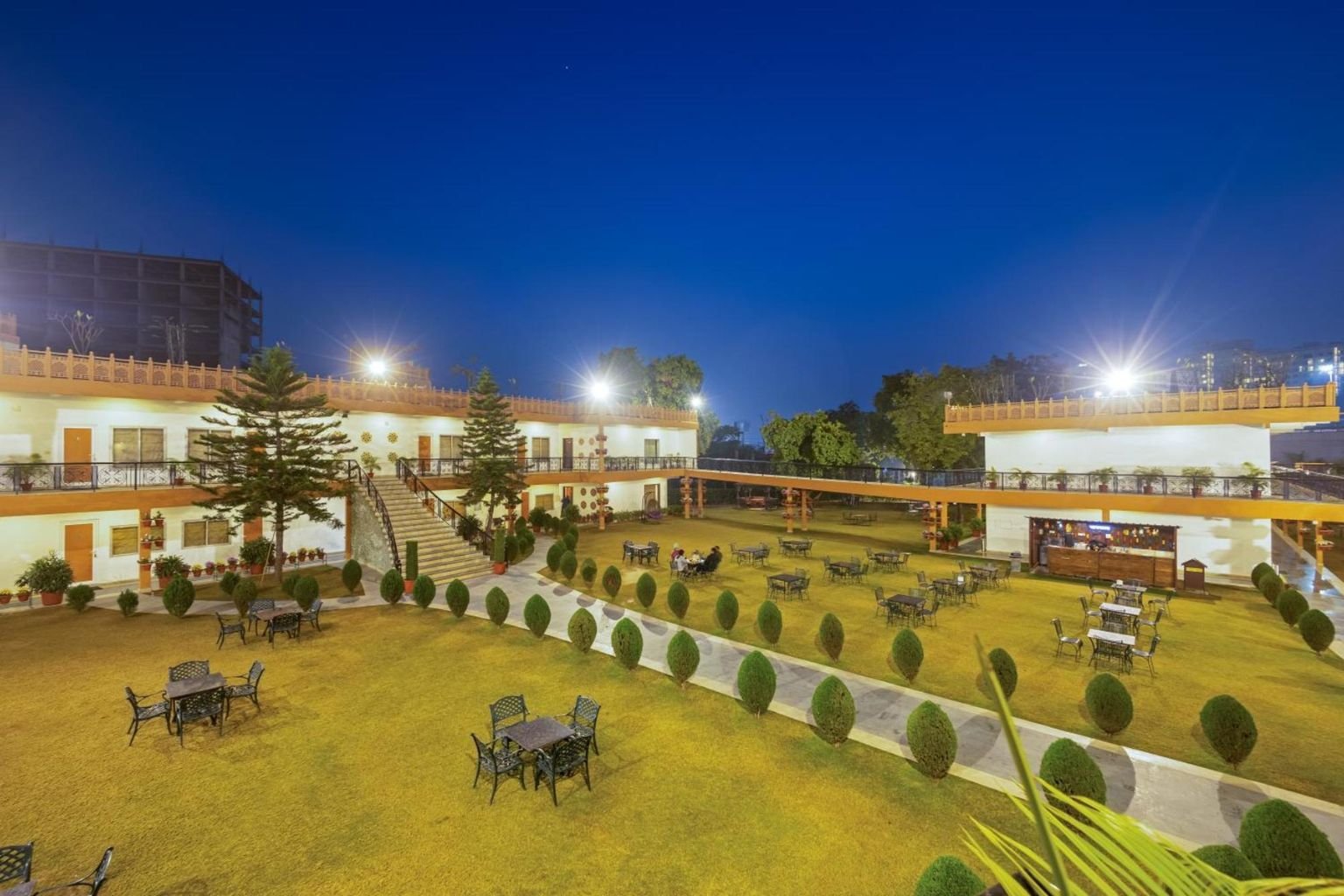Resort lawn and low-rise guest block in Manesar at dusk