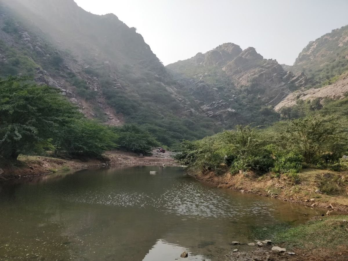 A calm, rock-lined waterbody among the low rocky hills near Bawal, Rewari district, Haryana
