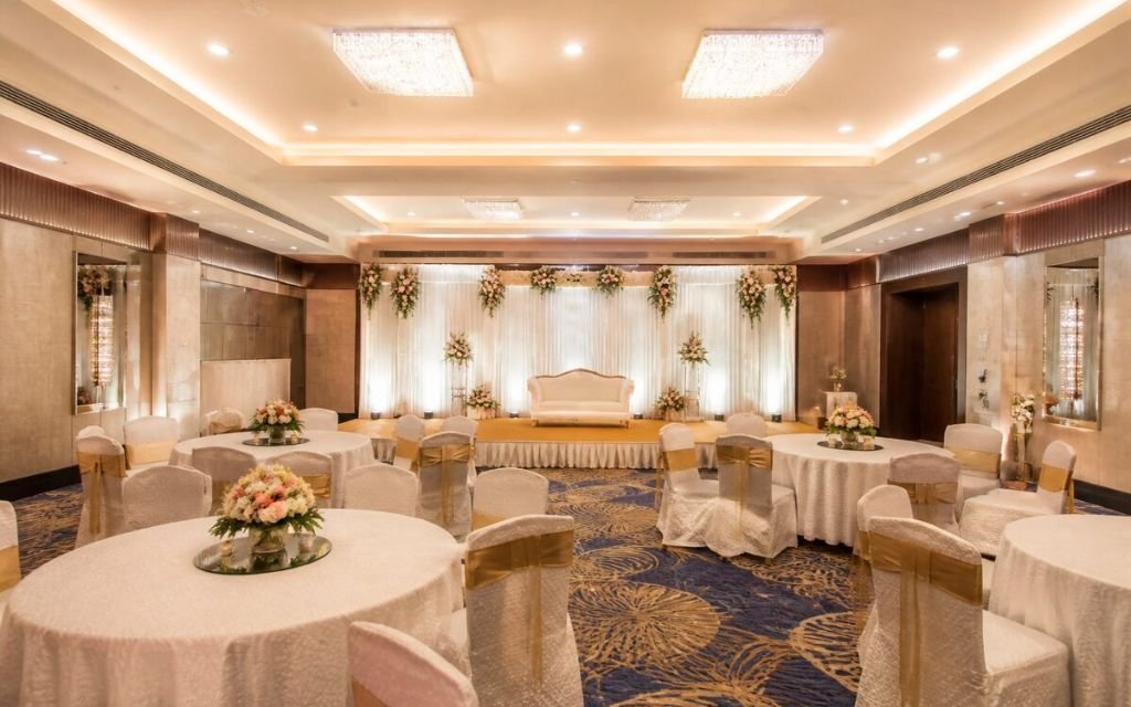 Air-conditioned banquet hall in Manesar with round-table seating and a decorated stage for an engagement function