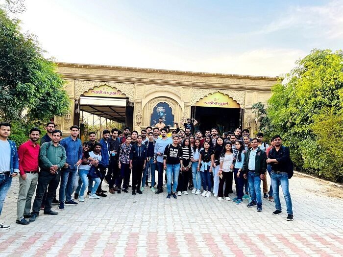 Large group of young visitors posing in the sandstone courtyard of Madhavgarh Farms