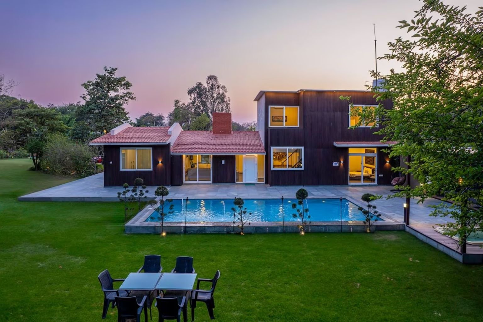 Luxury farmhouse with green lawn and swimming pool near Manesar at sunset