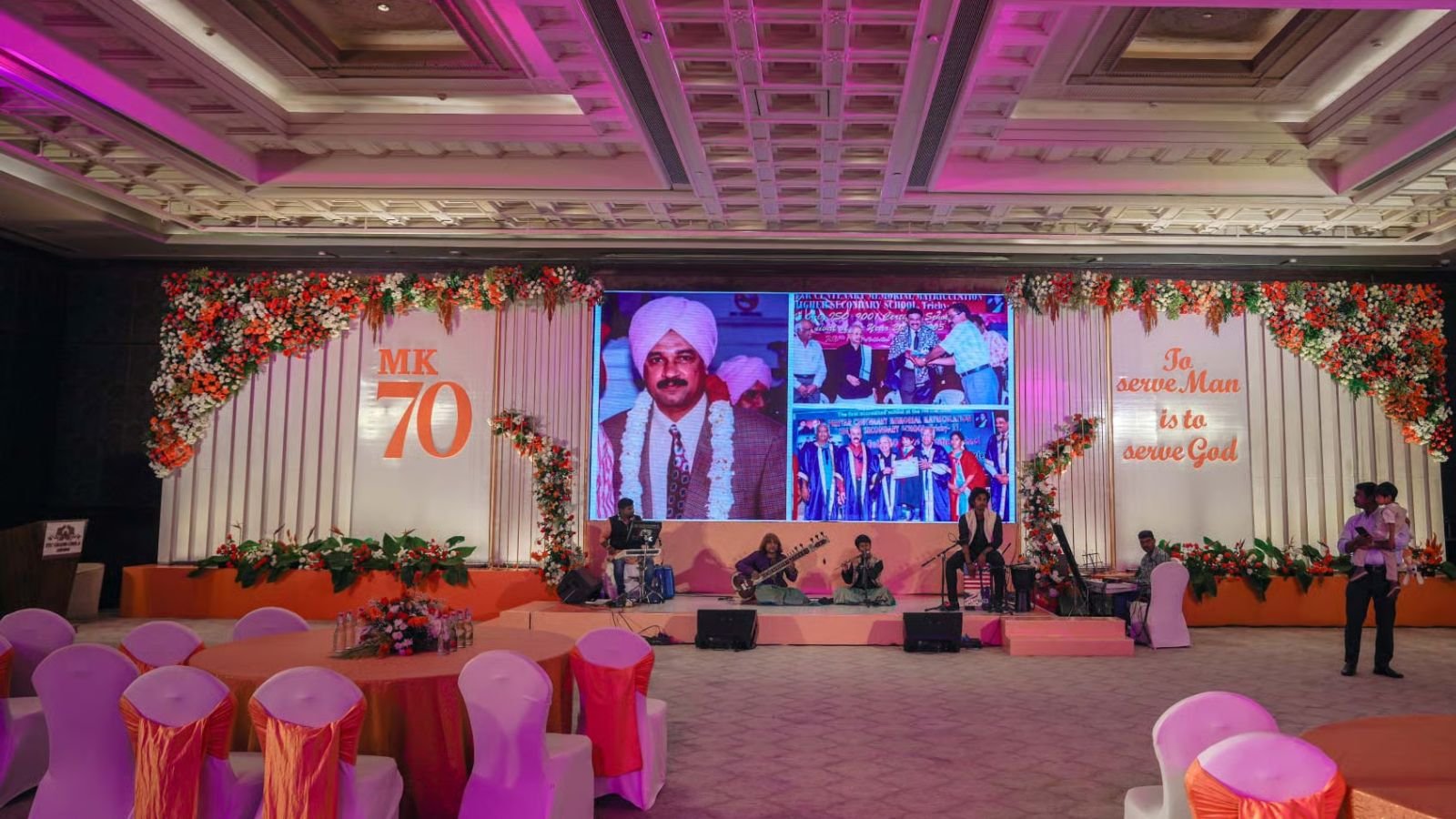 Party hall in Gurgaon decorated with a stage, warm lighting and table settings for a birthday celebration