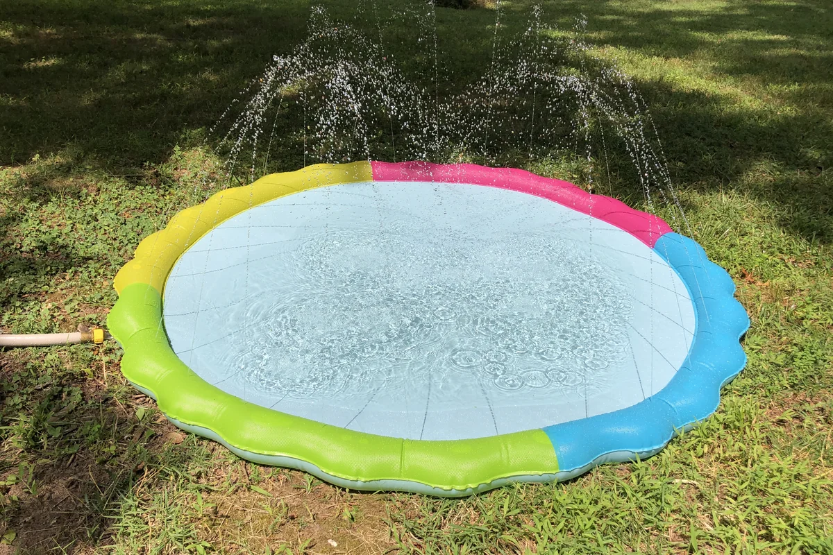 Children playing under water sprinklers on a lawn — representative photograph of splash-zone play