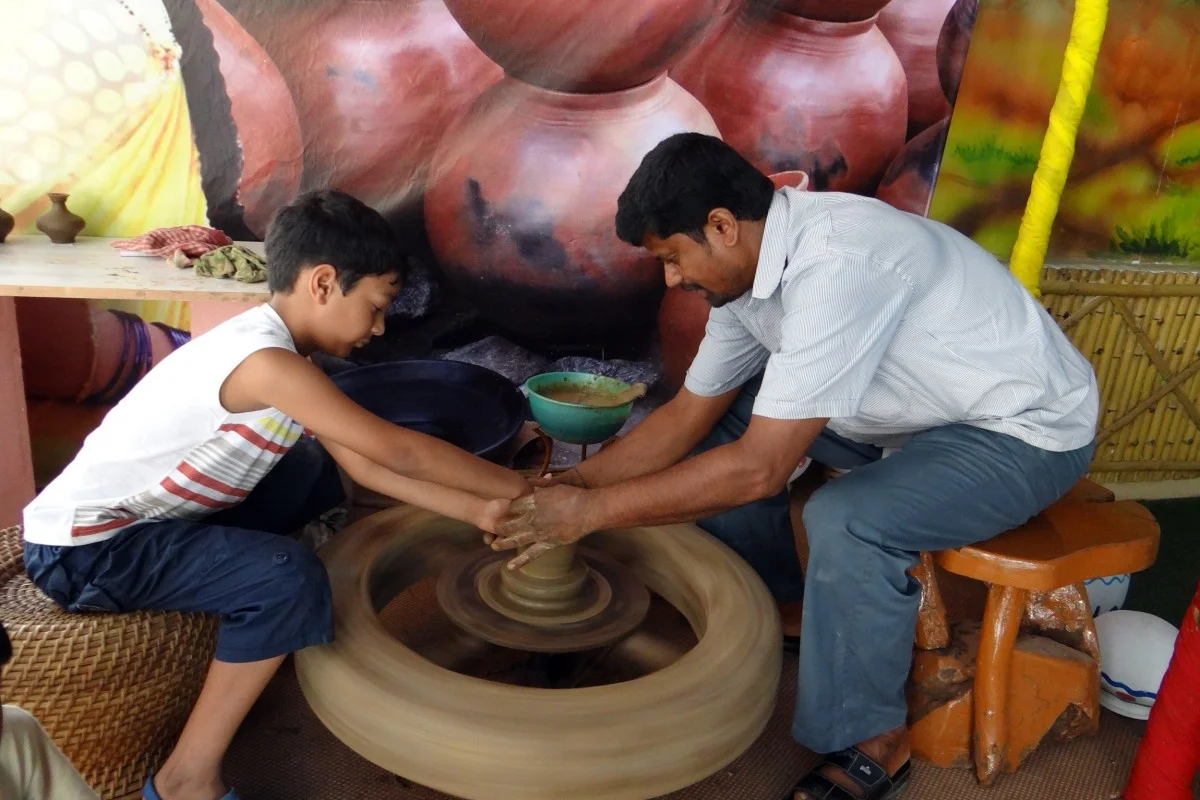Potter and a boy shaping a pot on a traditional wheel — representative photograph of a village craft